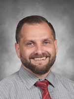 Bill Rodgers is wearing a gray dress shirt with a red tie.