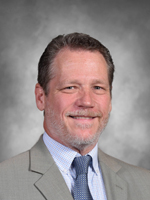 Ron Cole is wearing a gray business suit and tie